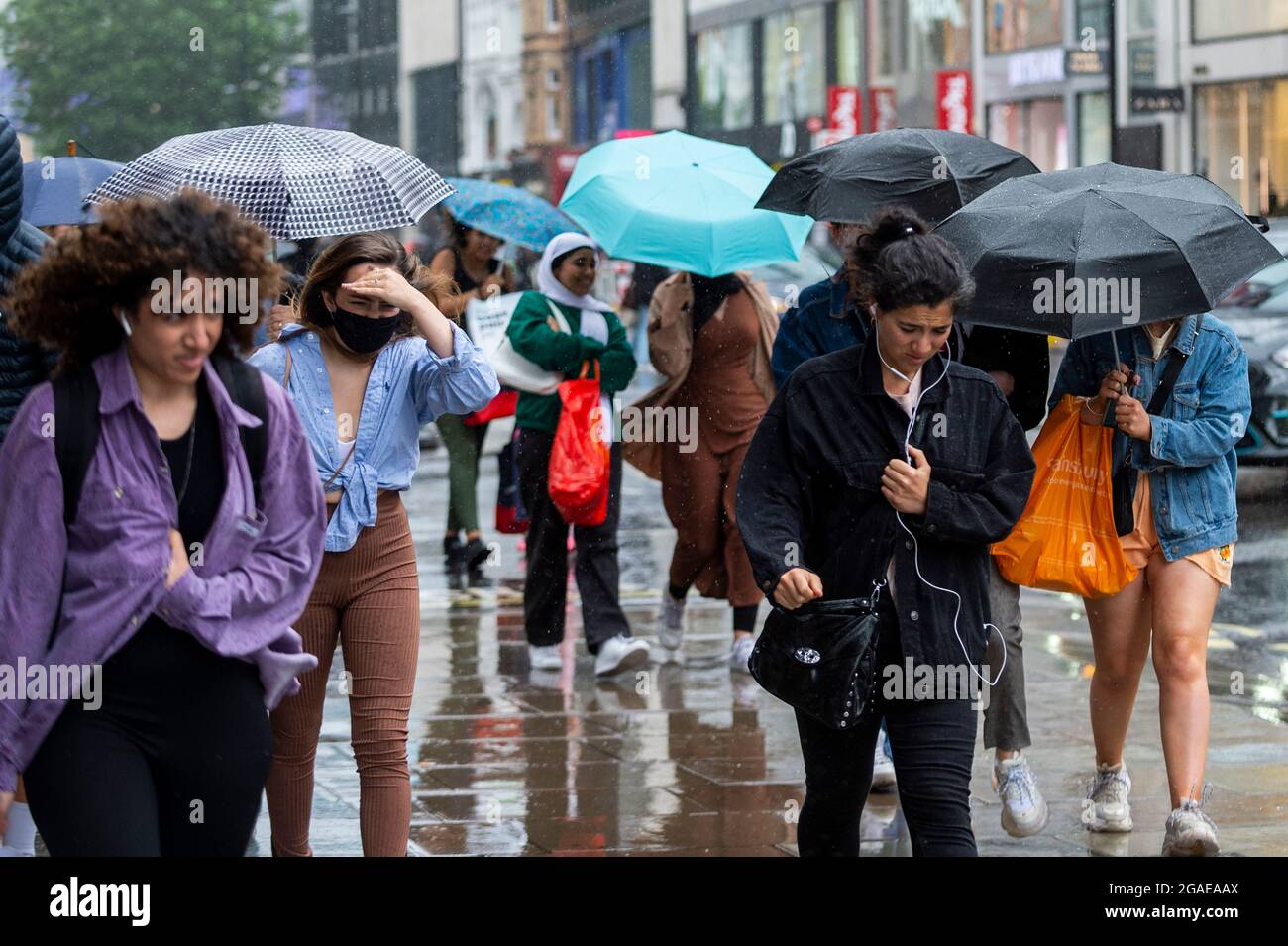 Londra, Regno Unito. 30 luglio 2021. Regno Unito Meteo - le persone di Oxford Street sperimentano condizioni di vento e pioggia mentre Storm Evert passa attraverso la capitale. Avvertenze gialle per vento e tempeste di tuoni sono in atto attraverso l'est e il sud-est dell'Inghilterra. Credit: Stephen Chung / Alamy Live News Foto Stock