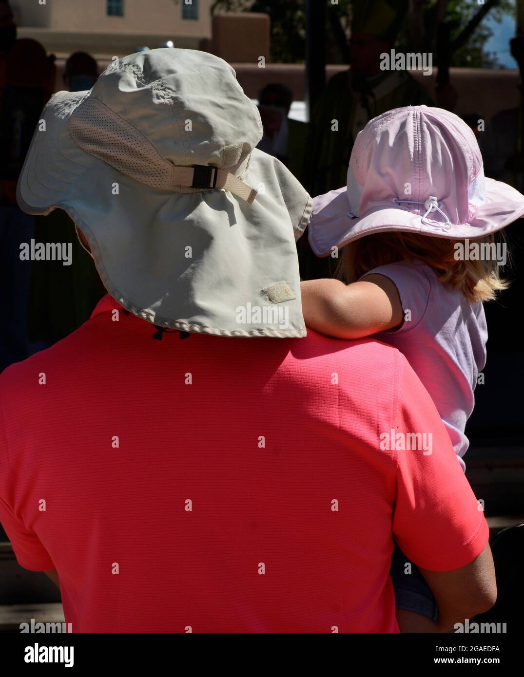 Un uomo e la sua giovane figlia indossano cappelli da sole protettivi mentre guardano un concerto all'aperto a Santa Fe, New Mexico. Foto Stock