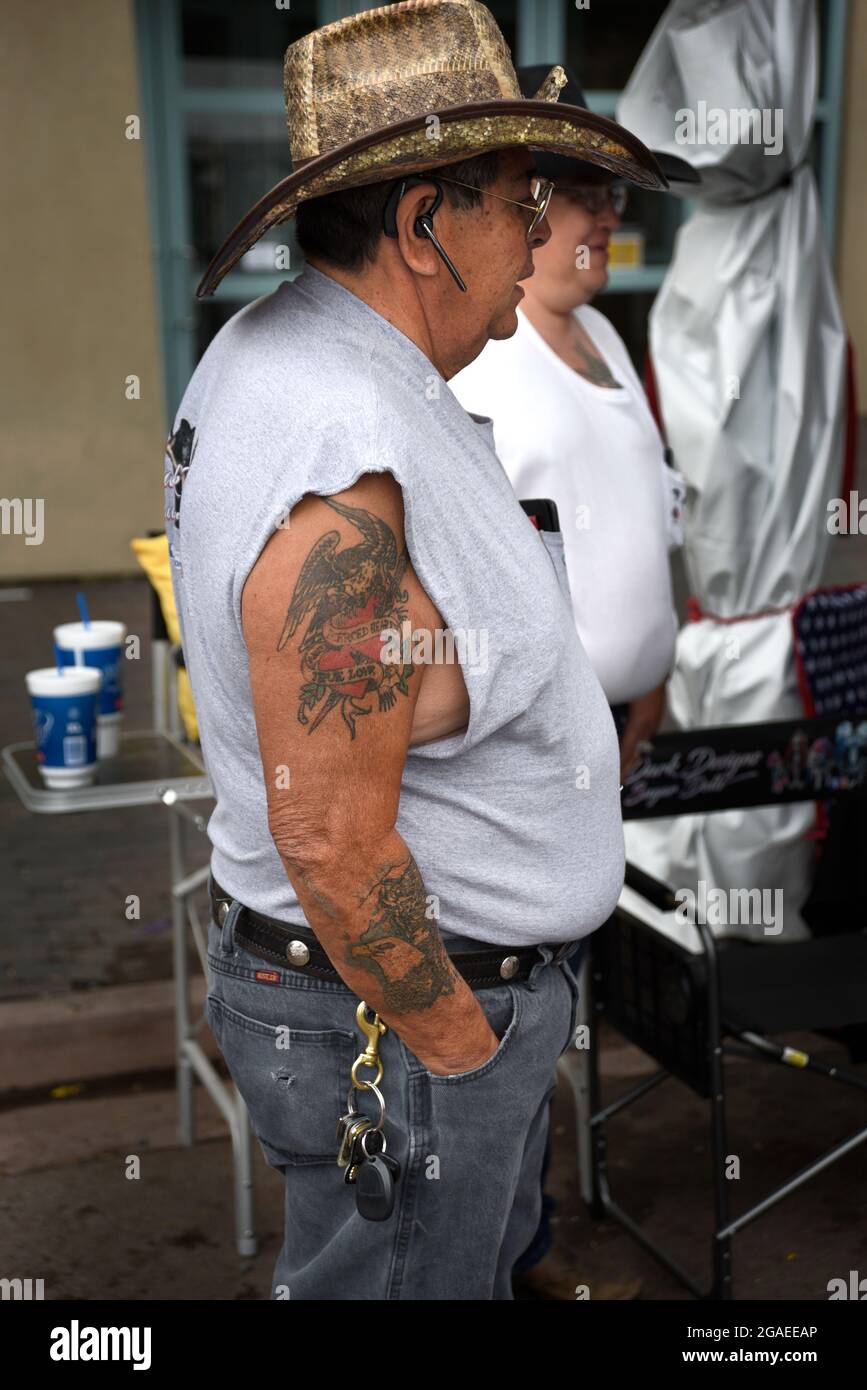 Un uomo con tatuaggi sul braccio visita una mostra d'arte all'aperto a Santa Fe, New Mexico. Foto Stock