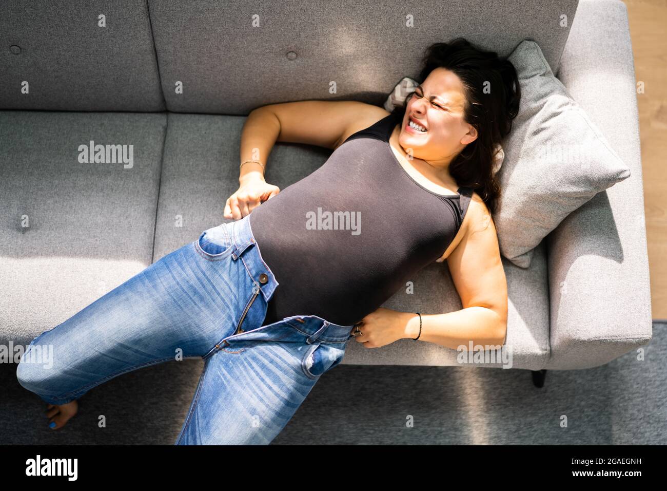 Donna che lotta con jeans stretti. Guadagno peso Foto stock - Alamy