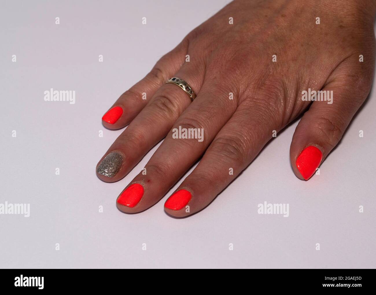 Signore mano destra con vernice rosso brillante unghie su quattro dita e un dito con argento puntinato Foto Stock