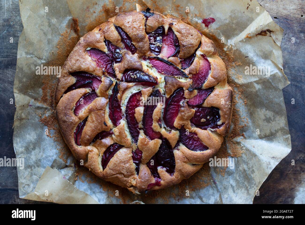 Tondare sulla tavola di legno la torta di prugne appena sfornata Foto Stock