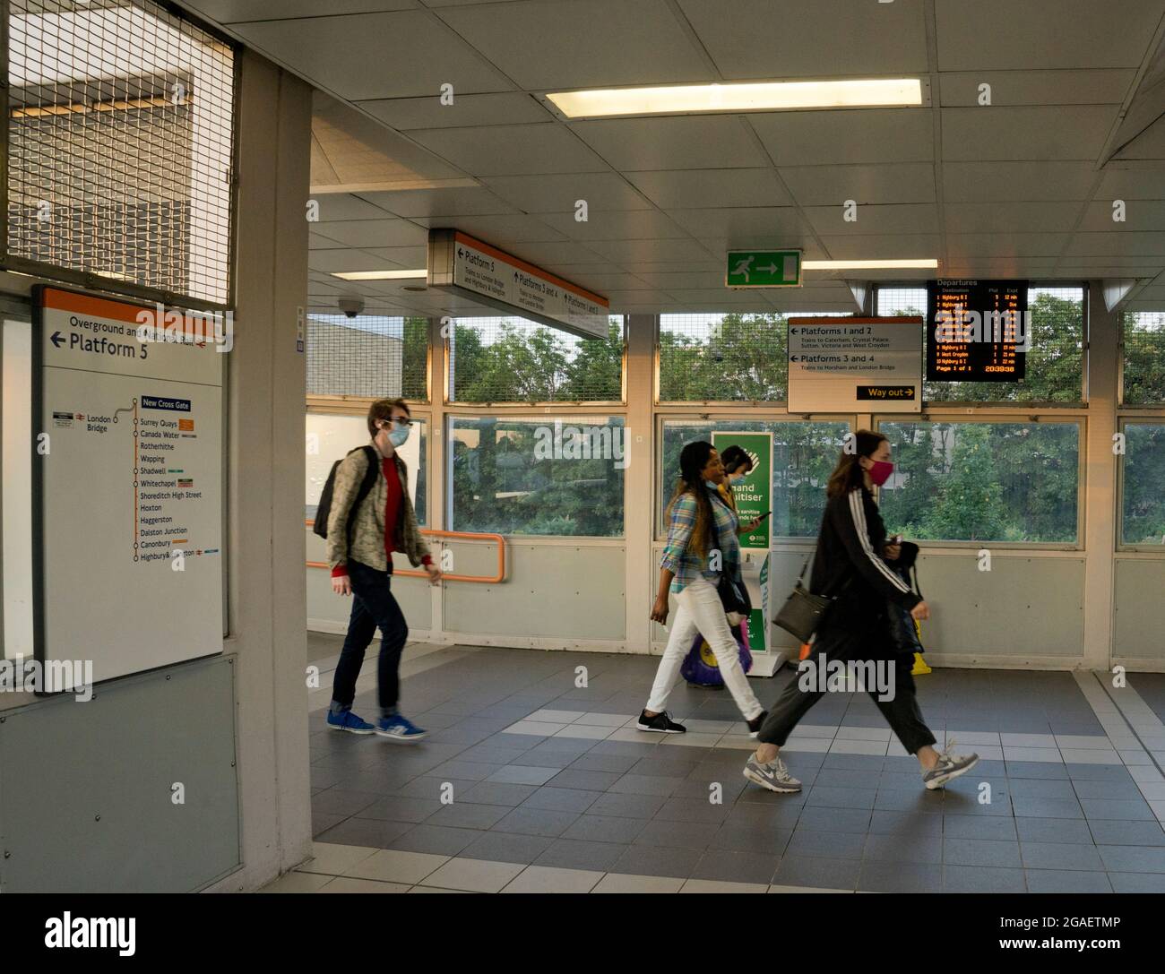 I passeggeri che indossano maschere a causa della pandemia COVID-19 per segno di lavoro in corso presso una linea Overground, Londra, Inghilterra, Regno Unito Foto Stock