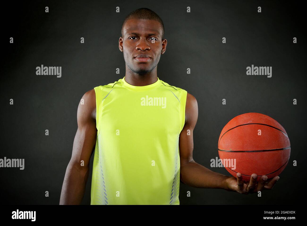 Giocatore di basket Africano Americano che tiene la palla su sfondo scuro Foto Stock