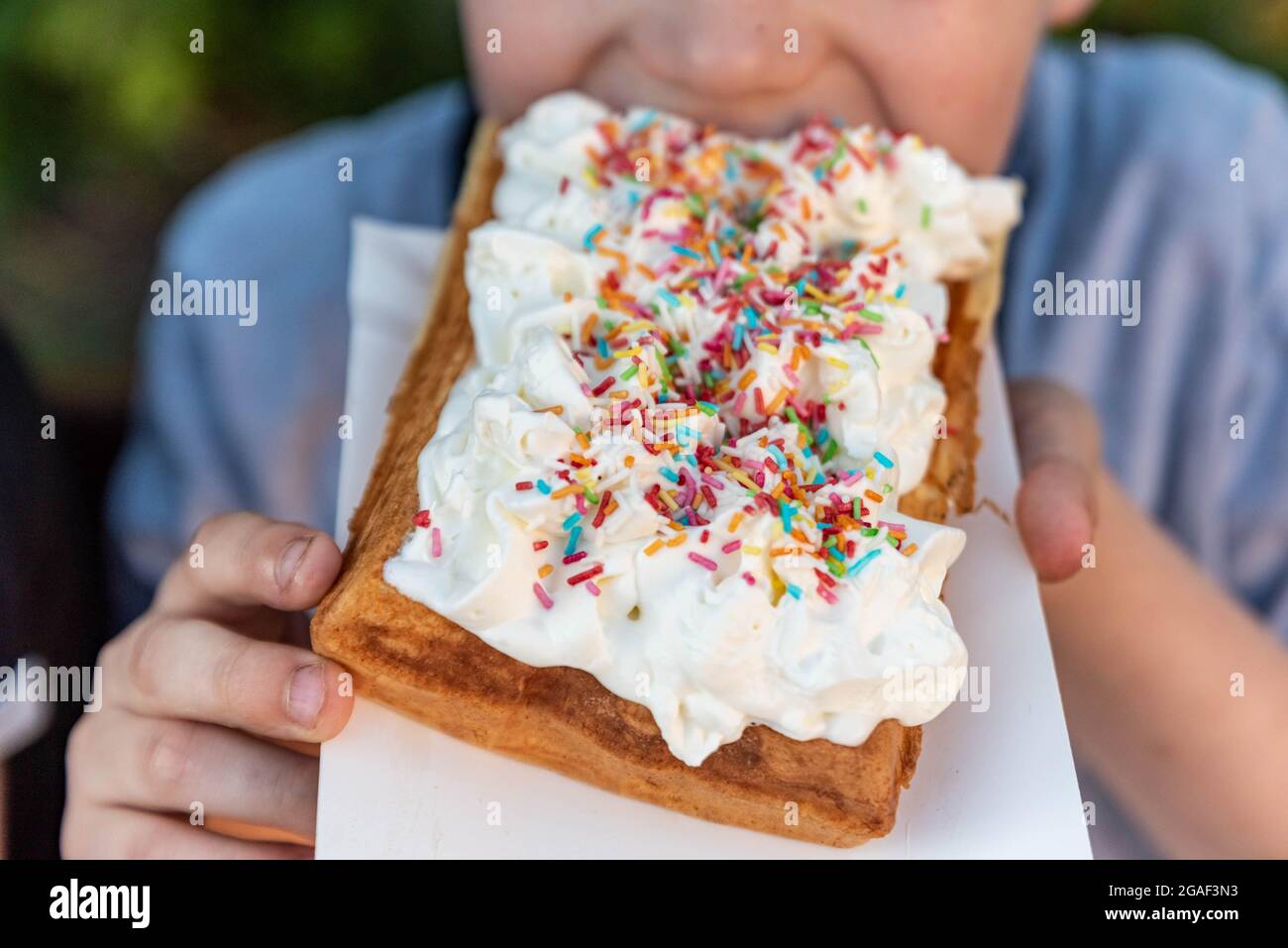 Waffle con panna montata e spolverini colorati, dessert per bambini. Spuntino dolce. Foto Stock