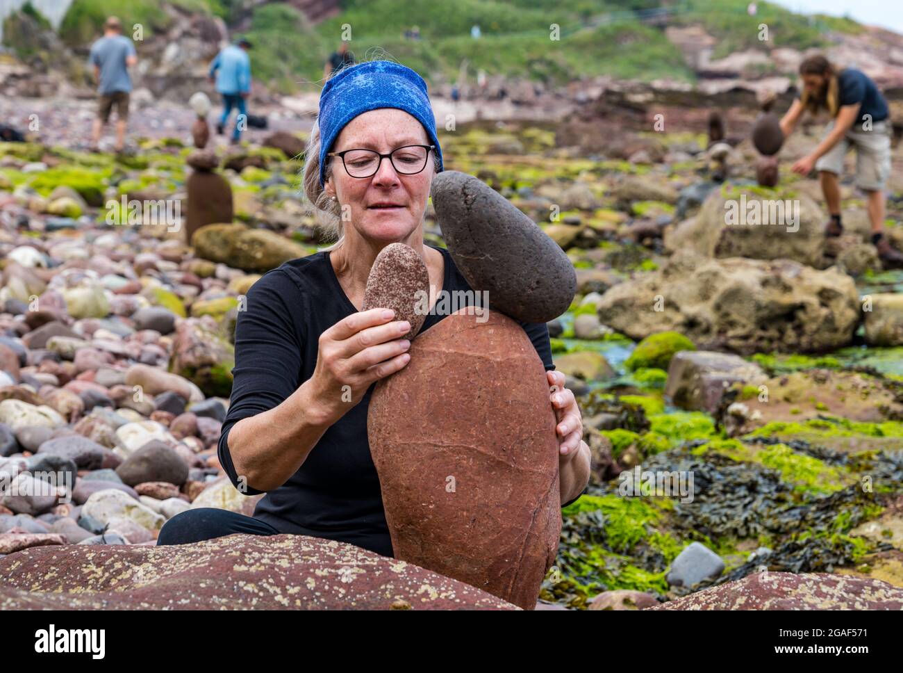 Caroline Walker, stacker di pietra, bilancia le pietre nel Campionato europeo di pietre impilate sulla spiaggia, Dunbar, East Lothian, Scozia, Regno Unito Foto Stock