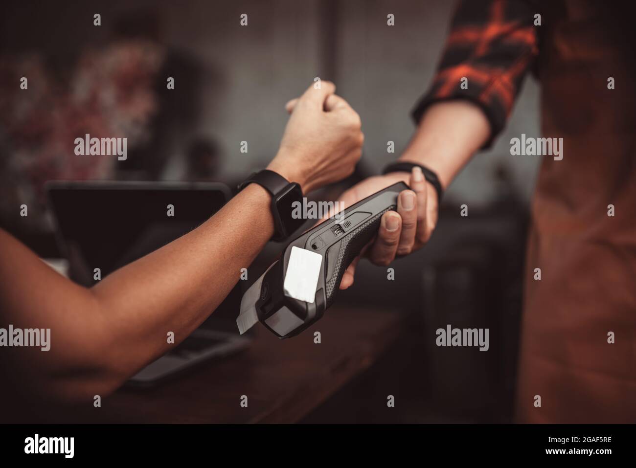 Pagamento smartwatch con lettore di carte di credito al bar Foto Stock