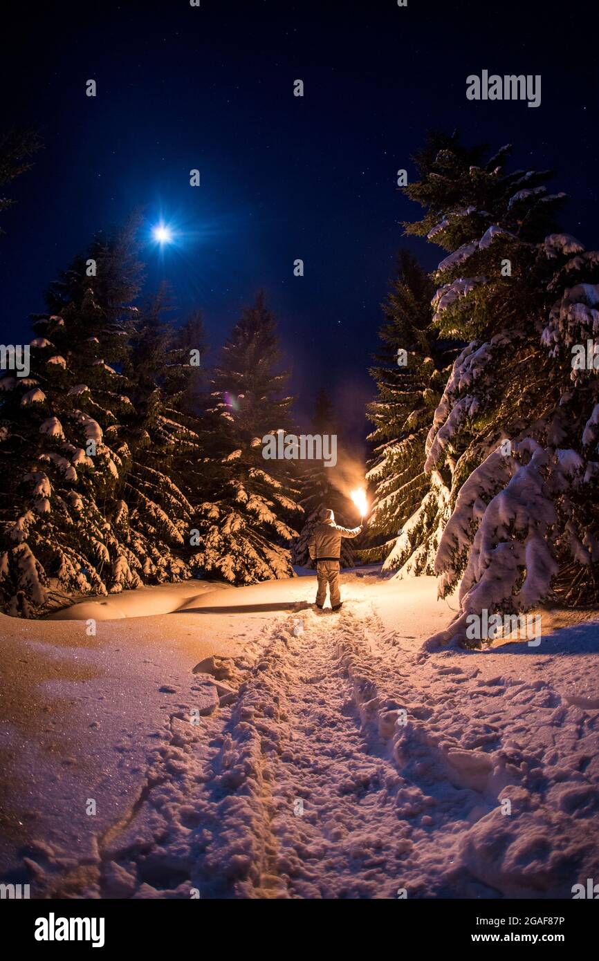Uomo con una torcia in montagna di notte nella neve Foto Stock