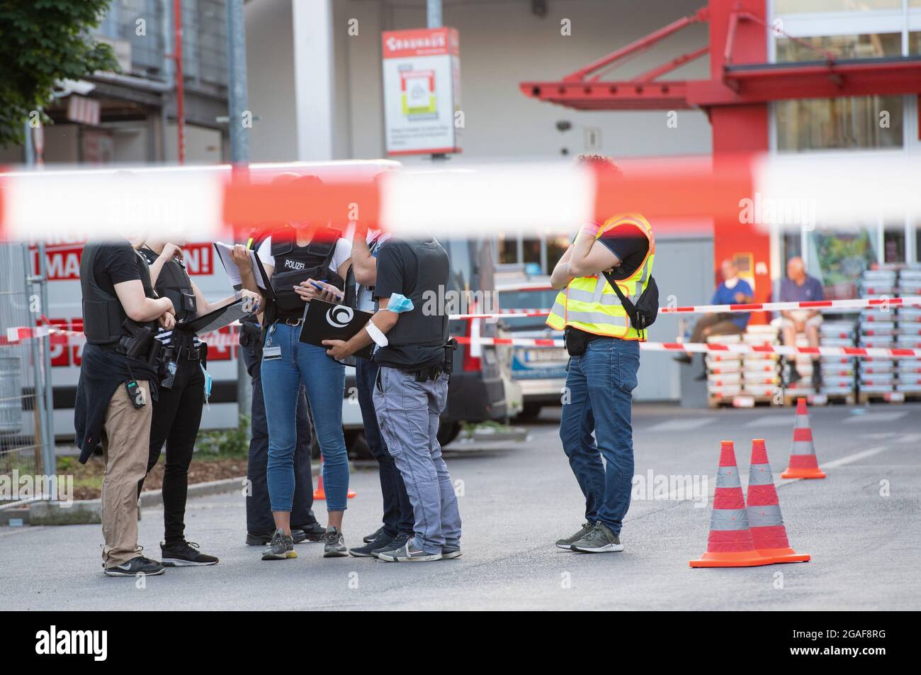 Berlino, Germania. 30 luglio 2021. Gli agenti di polizia si trovano dietro un cordone nel parcheggio di un negozio di ferramenta a Berlino-Wedding. Diversi colpi sono stati sparati nel parcheggio nel tardo Venerdì pomeriggio. Secondo il reparto vigili del fuoco, ci sono stati quattro feriti, tre uomini e una donna. Sono stati trattati in loco da medici e poi portati in ospedale, ha detto un portavoce del dipartimento dei vigili del fuoco. La polizia e i vigili del fuoco hanno risposto a un'operazione su larga scala. Credit: Paul Zinken/dpa-Zentralbild/dpa/Alamy Live News Foto Stock