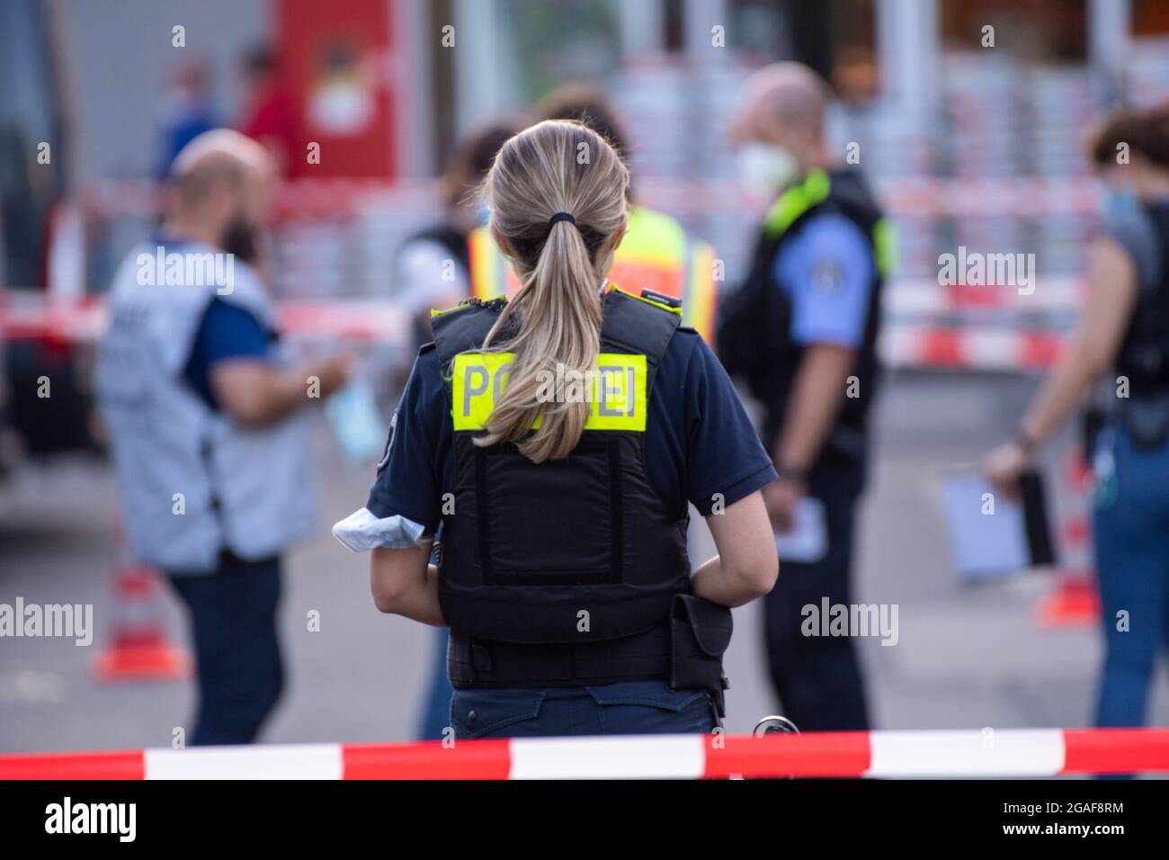 Berlino, Germania. 30 luglio 2021. Gli agenti di polizia si trovano dietro i nastri di protezione nei locali di un negozio fai da te a Berlino-Wedding. Diversi colpi sono stati sparati nel parcheggio nel tardo Venerdì pomeriggio. Secondo il reparto vigili del fuoco, ci sono stati quattro feriti, tre uomini e una donna. Sono stati trattati in loco da medici e poi portati in ospedale, ha detto un portavoce del dipartimento dei vigili del fuoco. La polizia e i vigili del fuoco hanno risposto a un'operazione su larga scala. Credit: Paul Zinken/dpa-Zentralbild/dpa/Alamy Live News Foto Stock