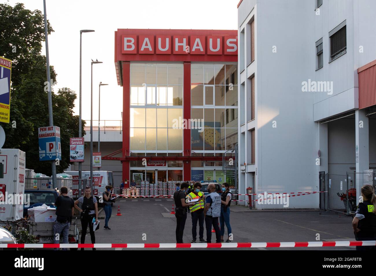 Berlino, Germania. 30 luglio 2021. Gli agenti di polizia si trovano dietro i nastri di protezione nei locali di un negozio fai da te a Berlino-Wedding. Diversi colpi sono stati sparati nel parcheggio nel tardo Venerdì pomeriggio. Secondo il reparto vigili del fuoco, ci sono stati quattro feriti, tre uomini e una donna. Sono stati trattati in loco da medici e poi portati in ospedale, ha detto un portavoce del dipartimento dei vigili del fuoco. La polizia e i vigili del fuoco hanno risposto a un'operazione su larga scala. Credit: Paul Zinken/dpa-Zentralbild/dpa/Alamy Live News Foto Stock