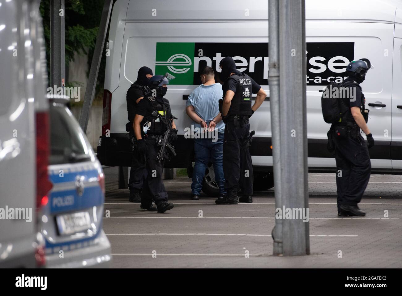 Berlino, Germania. 30 luglio 2021. Gli agenti di polizia si trovano accanto a un colpevole sospettato sulla base di un negozio di ferramenta a Berlino-Wedding dopo il suo arresto. Diversi colpi sono stati sparati nel parcheggio nel tardo Venerdì pomeriggio. Secondo il reparto vigili del fuoco, ci sono stati quattro feriti, tre uomini e una donna. Sono stati trattati in loco da medici e poi portati in ospedale, ha detto un portavoce del dipartimento dei vigili del fuoco. La polizia e i vigili del fuoco hanno risposto a un'operazione su larga scala. Credit: Paul Zinken/dpa-Zentralbild/dpa/Alamy Live News Foto Stock