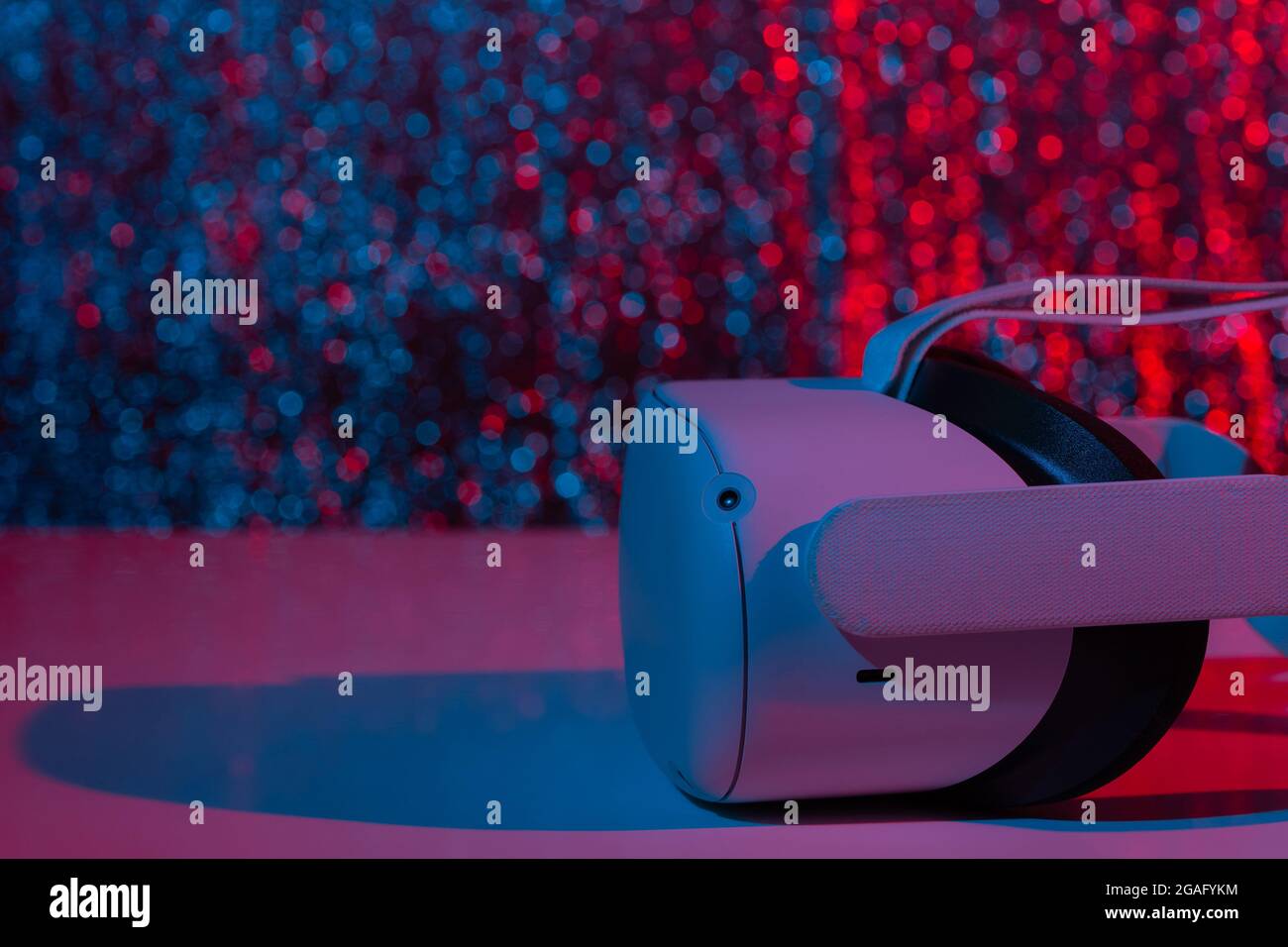 Casco per realtà virtuale su sfondo bianco con luce al neon. Realtà virtuale, futuro, gadget, concetto di tecnologia. Foto Stock