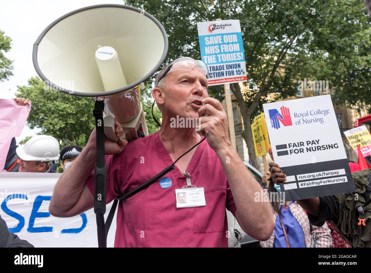 David Carr, un infermiere responsabile presso il NHS Foundation Trust, parla ai dimostranti su un megafono durante la dimostrazione fuori da Downing Street. I membri del National Health Service (NHS) si sono riuniti fuori dal St. Thomas' Hospital prima di marciare verso Downing Street in una dimostrazione che richiede una retribuzione equa per i lavoratori NHS, poiché l'aumento retributiva del 3% rivisto dal governo è stato ritenuto poco soddisfacente. Le questioni affrontate includevano orari di lavoro lunghi, personale insufficiente e mancanza di materiali di protezione adeguati per gli operatori sanitari. La manifestazione è stata guidata da lavoratori NHS dire No, sostenuto dall'Unione unita, GMB Foto Stock