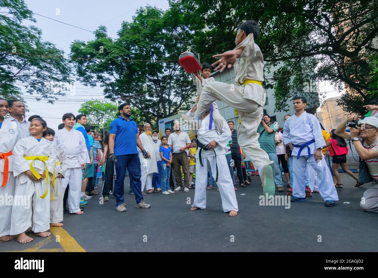 KOLKATA, BENGALA OCCIDENTALE, INDIA - 29 MARZO 2015 : ragazzo vestito bianco che salta in aria per calciare, karate di preghiera - evento 'Happy Street' su Park Street, Kolk Foto Stock