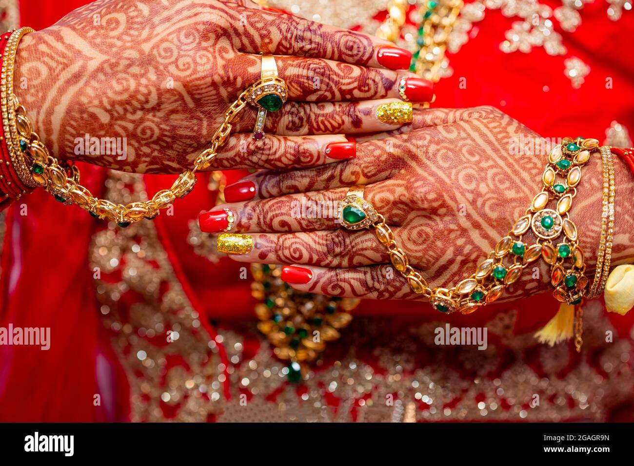 Tradizionali gioielli nuziale e decorazione henné sulle mani della sposa durante una cerimonia religiosa a nozze indù Foto Stock