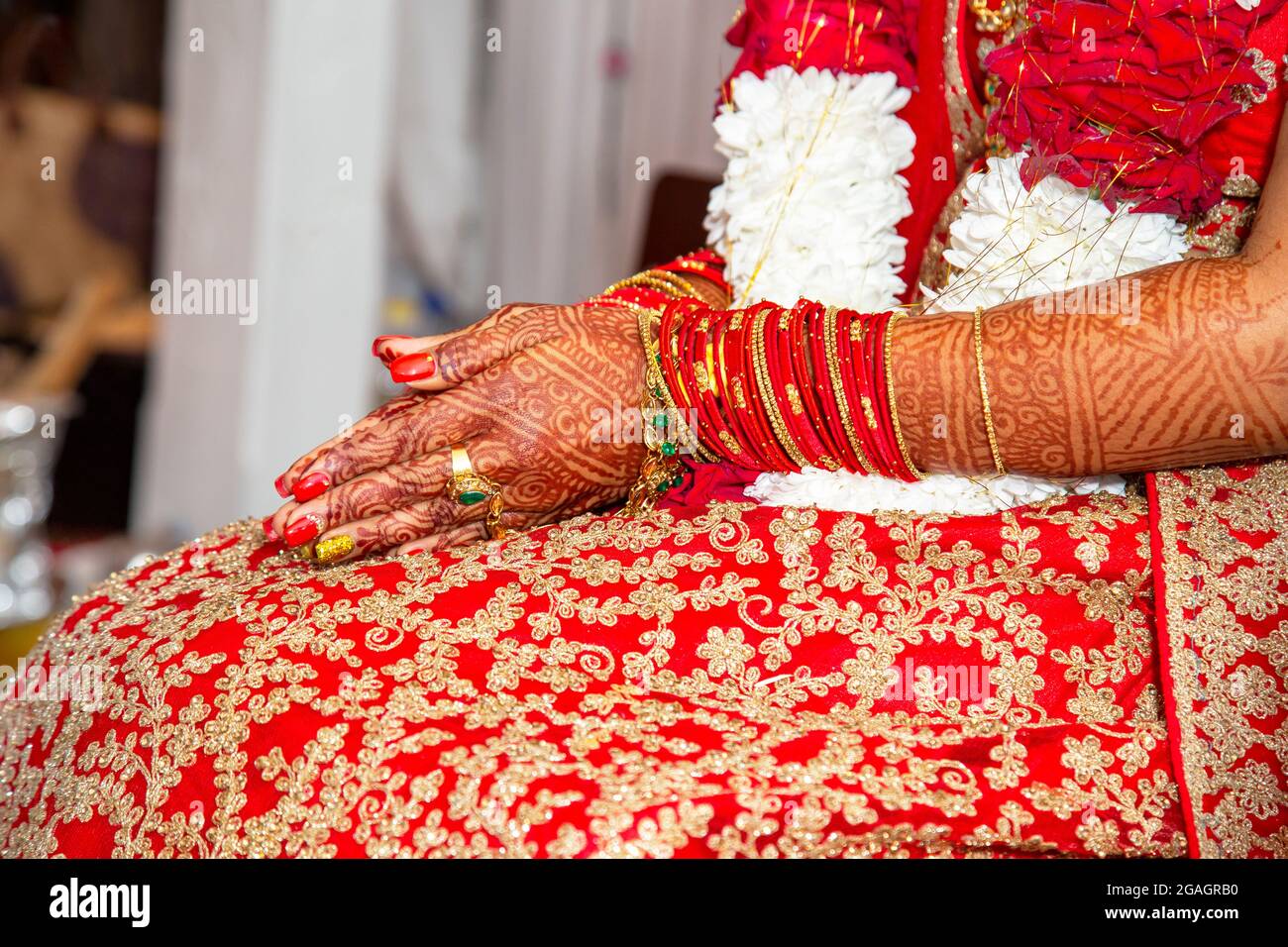 Tradizionali gioielli nuziale e decorazione henné sulle mani della sposa durante una cerimonia religiosa a nozze indù Foto Stock