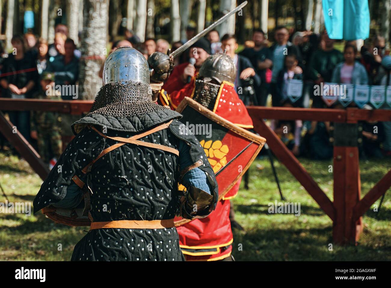 Ricostruzione di cavalieri nell'arena. Combatti di fronte al pubblico. Due cavalieri in armatura e con spade. Bishkek, Kirghizistan - 13 ottobre 2019 Foto Stock