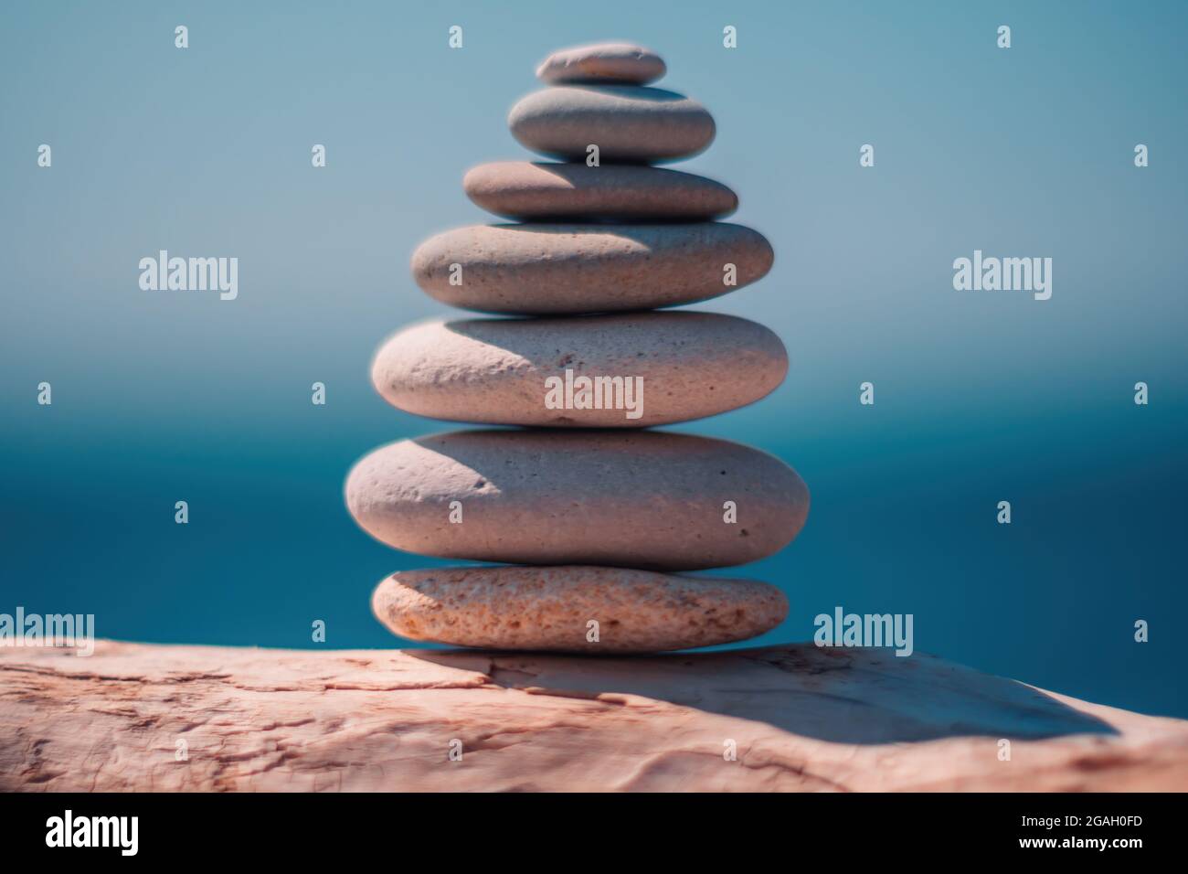 Equilibrata piramide di ciottoli sulla spiaggia in una giornata di sole. Abstract Sea bokeh sullo sfondo. Messa a fuoco selettiva. Pietre Zen sulla spiaggia di mare, meditazione Foto Stock