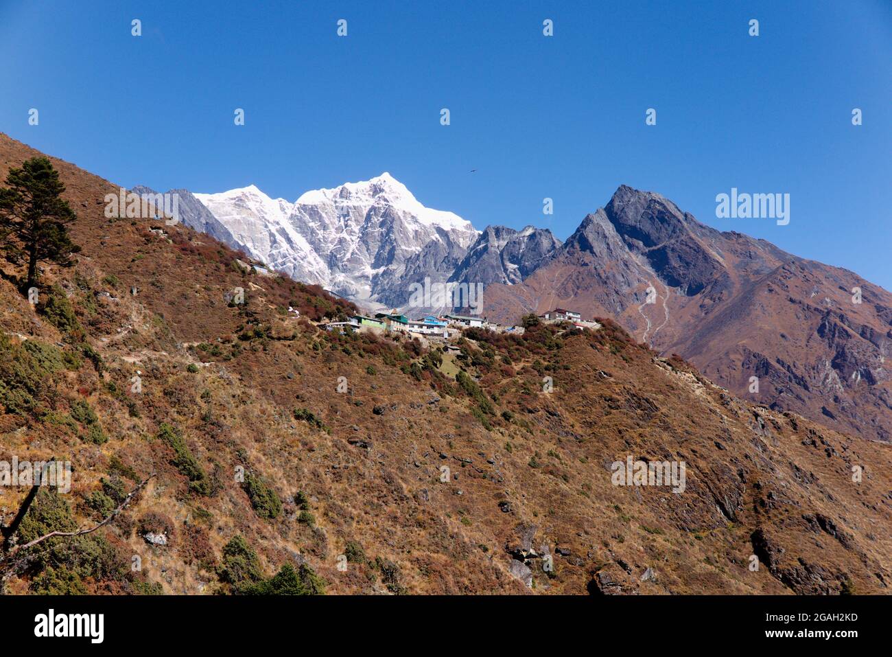 Vista del villaggio di Dole e le cime innevate di Kangtega e Thamserku sullo sfondo, lungo l'Everest base Camp Trek, Nepal Foto Stock