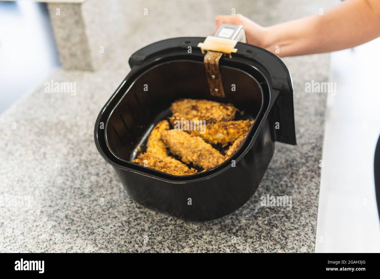 Primo piano della mano della donna utilizzando una friggitrice ad aria con  pollo fritto in pastella di cereali Foto stock - Alamy