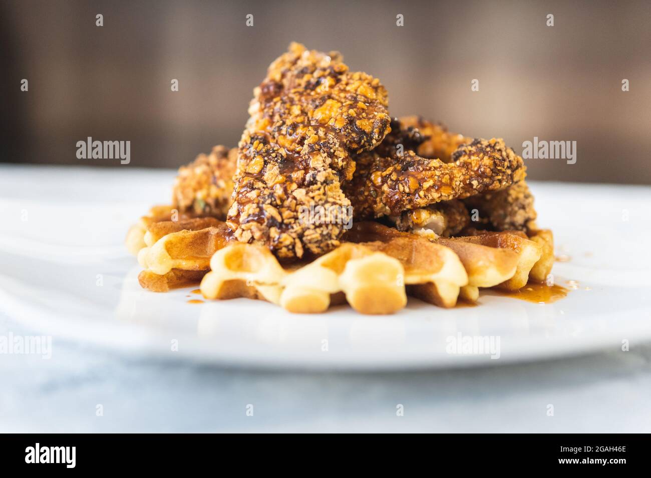 Pollo fritto impanato con cereali e waffle con salsa al barbecue Foto Stock