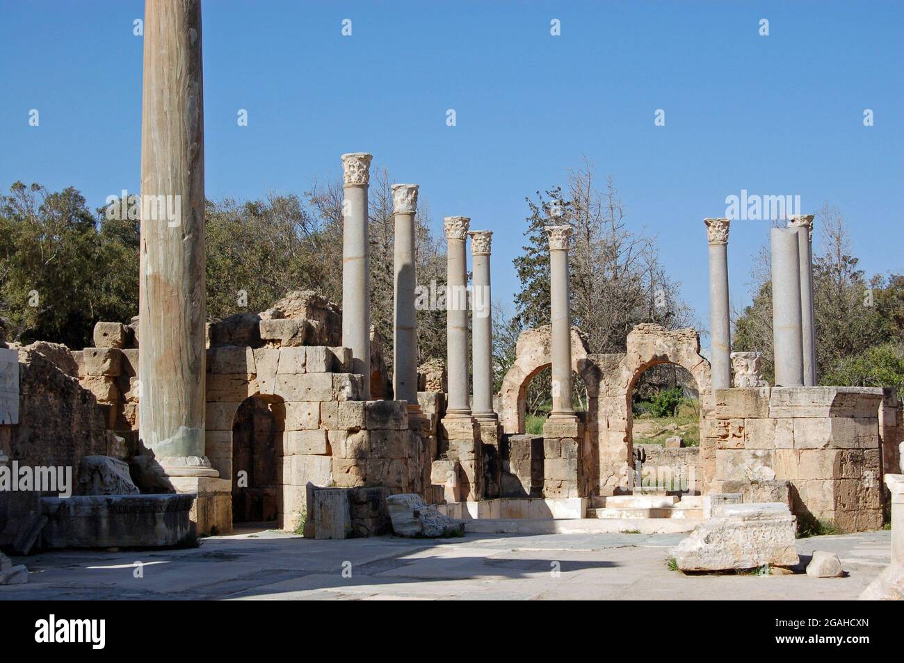 Colonne e rovine presso le storiche terme adrianiche, parte dell'antica città romana di Leptis Magna nel nord della Libia. Foto Stock