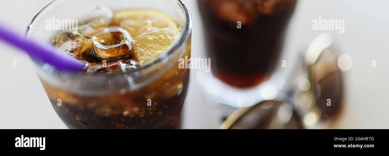 Due bicchieri con ghiaccio di cola e limone sono sul tavolo Foto Stock