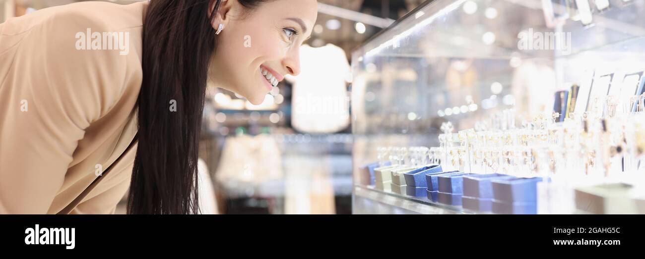 Sorridente giovane donna guarda vetrina con gioielli Foto Stock