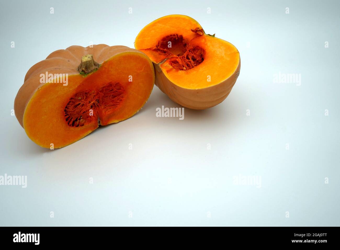 Una zucca o zucca tagliata in due metà isolato con un sacco di spazio di copia. Verdure di stagione di colore arancio brillante e' a contrasto. Foto Stock