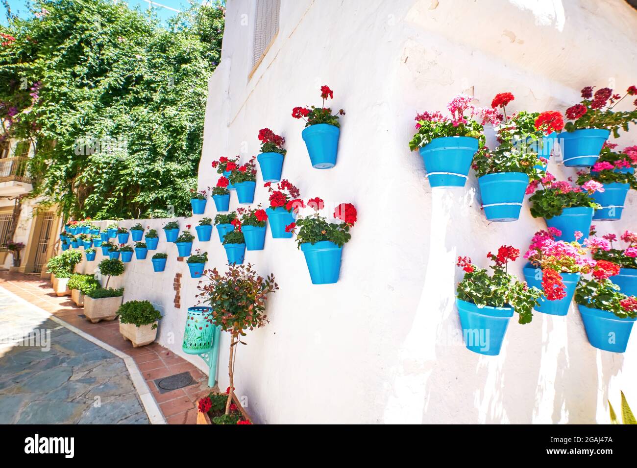 Bella città vecchia di Marbella in una giornata estiva soleggiata. Pareti bianche decorate con vaso di fiori blu. Foto Stock