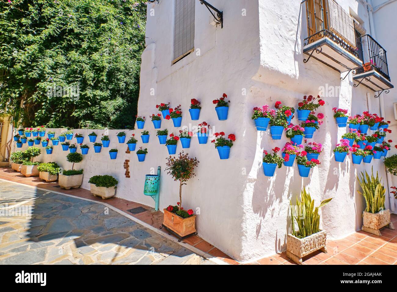 Bella città vecchia di Marbella in una giornata estiva soleggiata. Pareti bianche decorate con vaso di fiori blu. Foto Stock