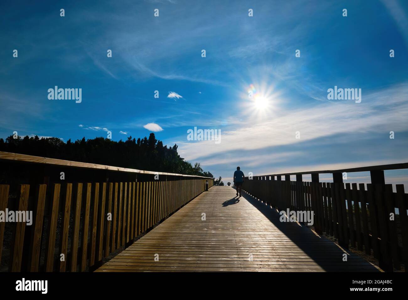 Splendida alba dal lungomare di legno con la silhouette di un uomo che cammina Foto Stock
