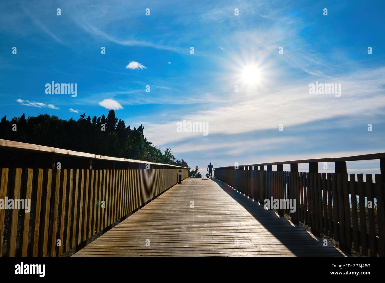 Splendida alba dal lungomare di legno con la silhouette di un uomo che cammina Foto Stock