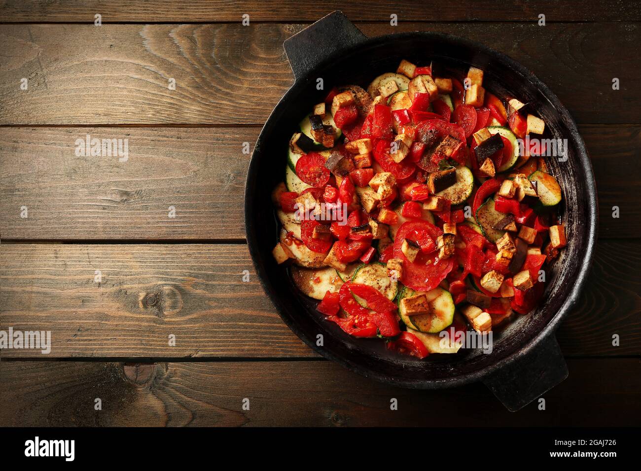 Gustosa ratatouille vegetariana a base di melanzane, squash, pomodori e  cipolle in padella di ghisa nera, sullo sfondo del tavolo in legno Foto  stock - Alamy