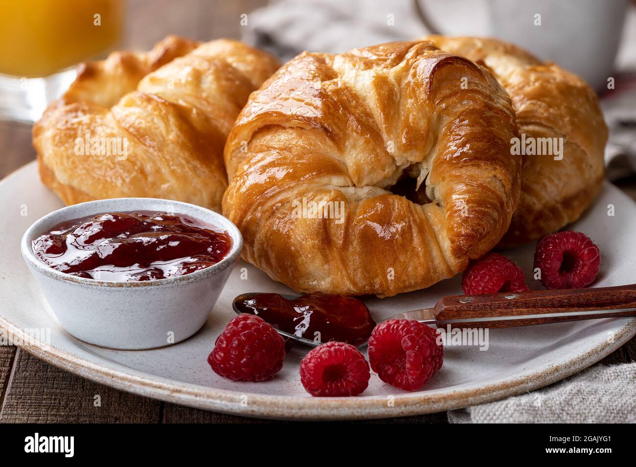 Primo piano di croissant con conserve di lamponi e lamponi freschi su un piatto Foto Stock