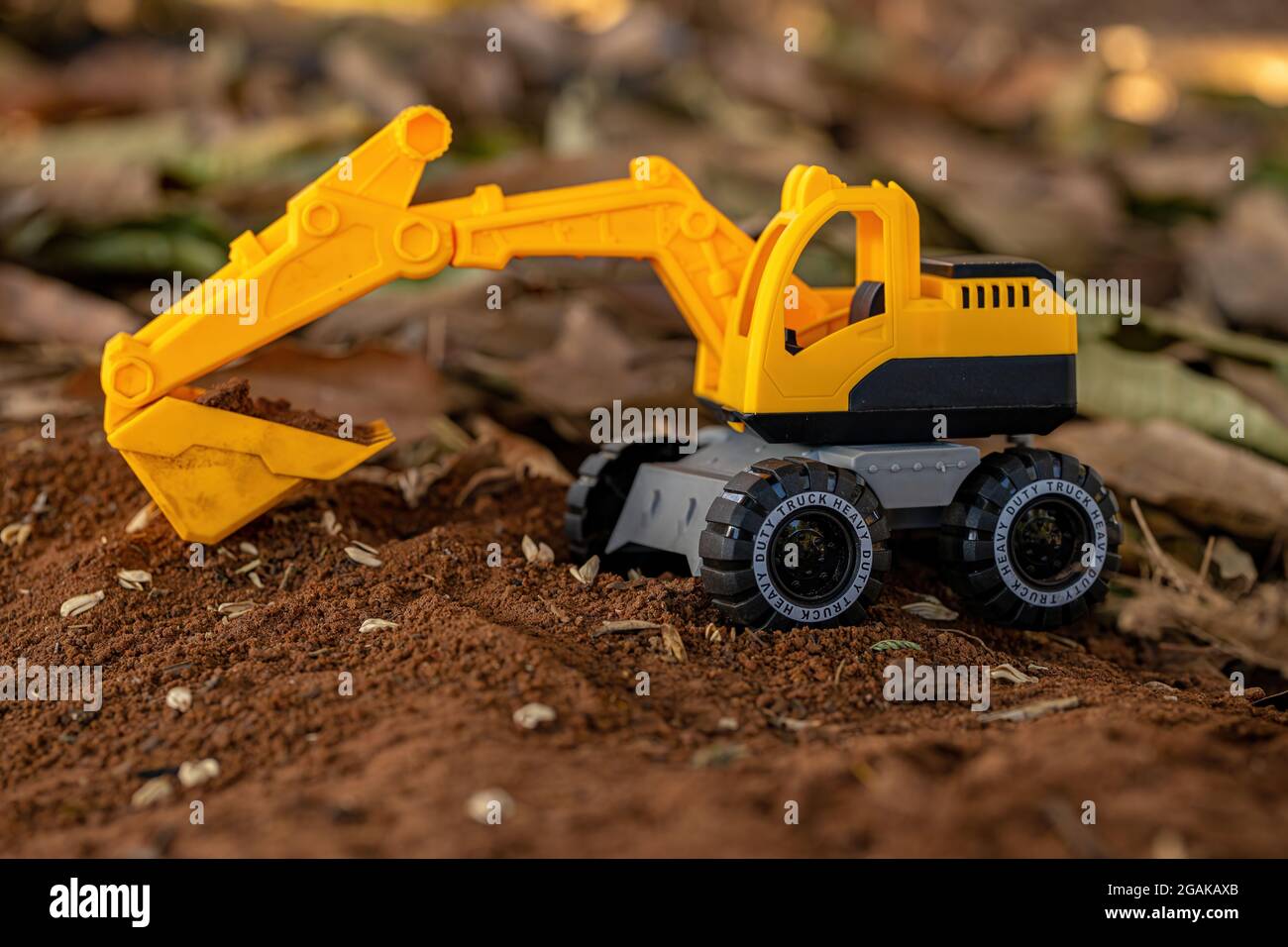Escavatore giocattolo in miniatura di colore giallo e nero a terra con  messa a fuoco selettiva Foto stock - Alamy