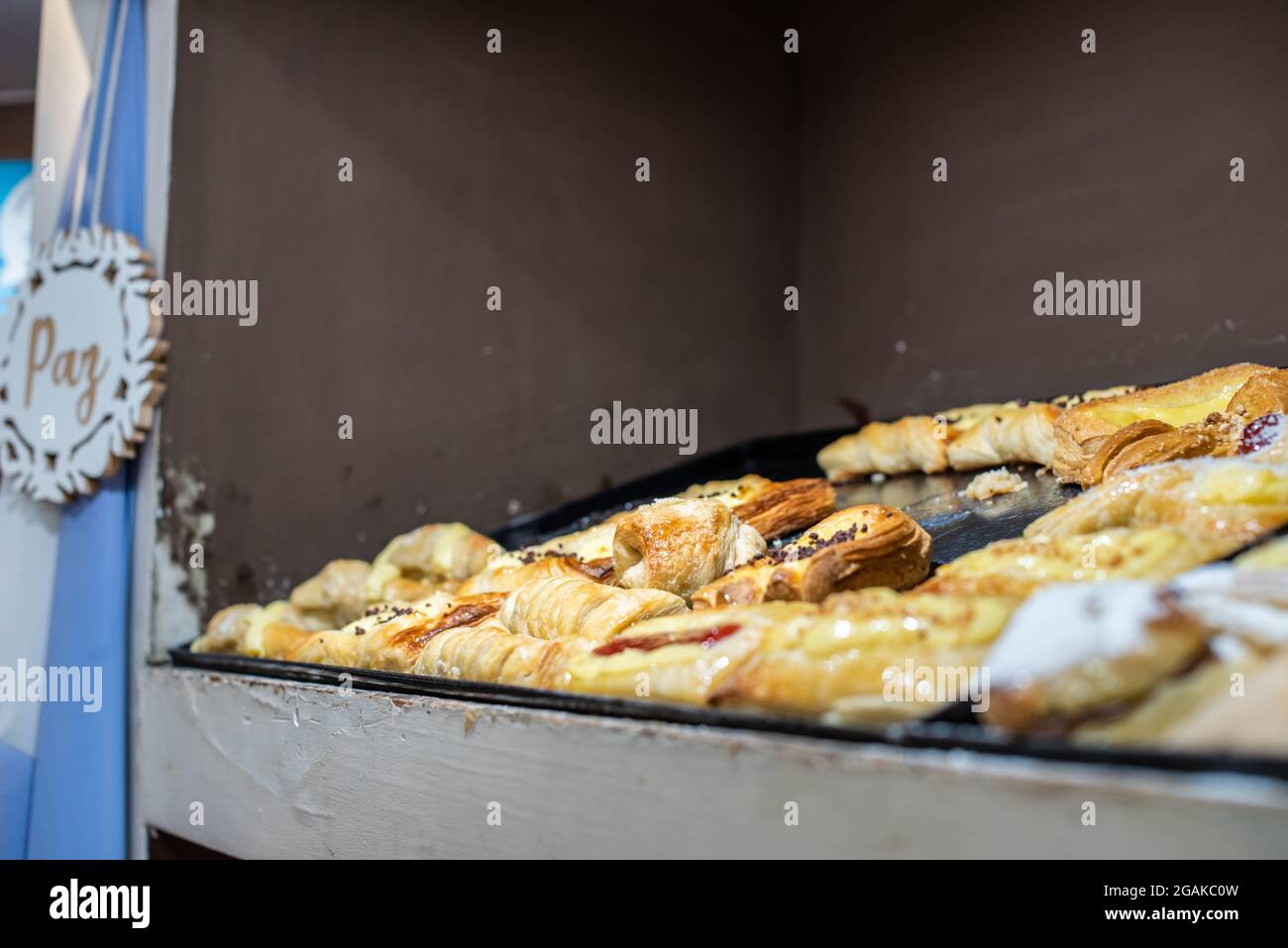 Mujer caucásica masando masa para hacer pan y bizcochos en una mesa color madera con luz de día, en una panadería. Foto Stock