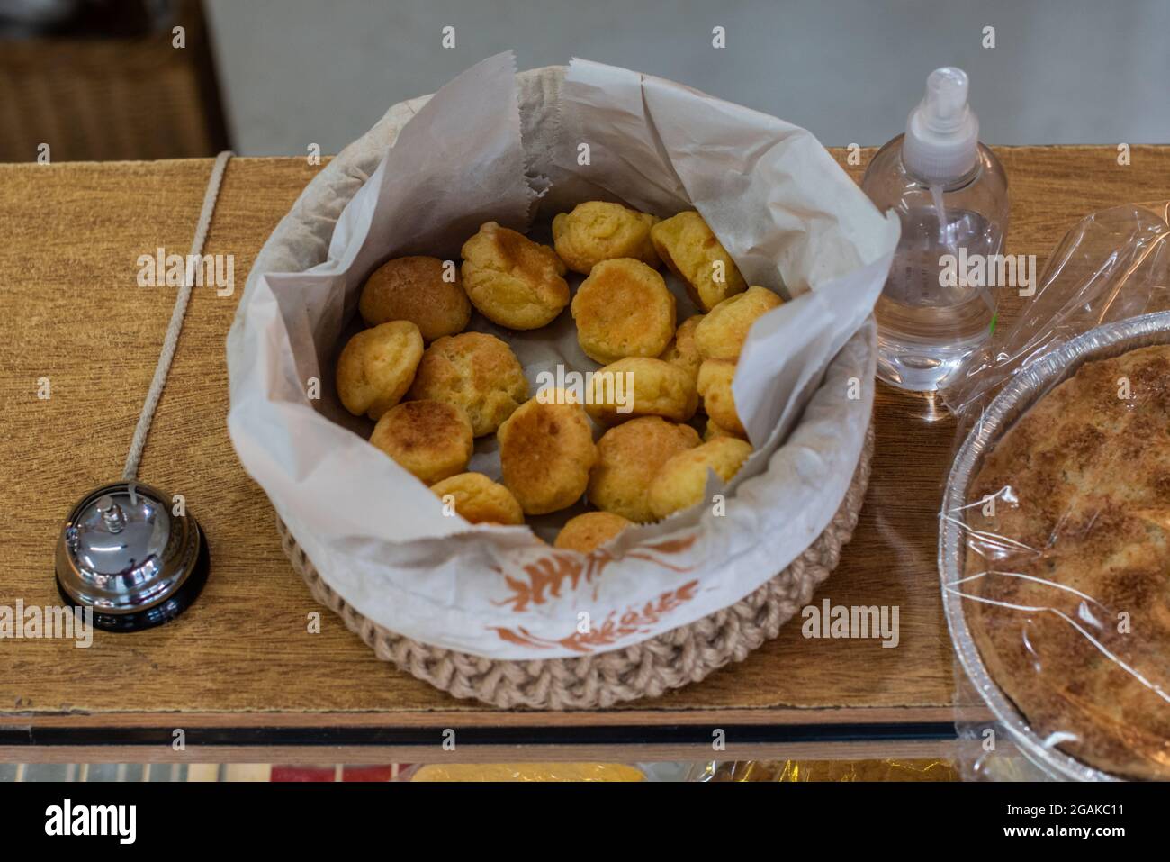 Mujer caucásica masando masa para hacer pan y bizcochos en una mesa color madera con luz de día, en una panadería. Foto Stock