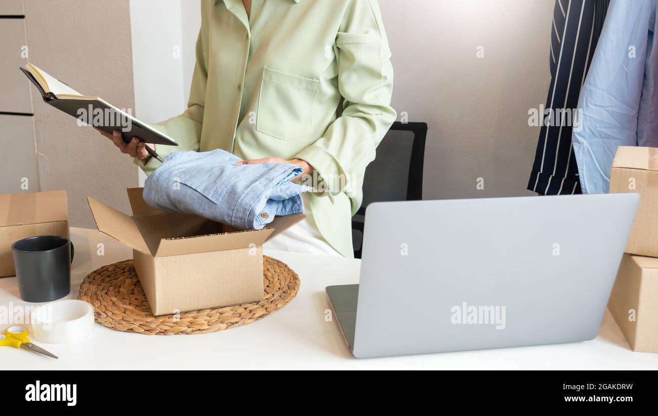 Il proprietario asiatico di affari che lavora a casa con la scatola di imballaggio del suo deposito in linea prepara per trasportare i prodotti ai clienti, lo stile di vita di generazione dell'alfa concep Foto Stock