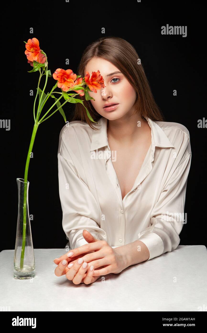 Giovane donna che nasconde il viso dietro fiori freschi Foto Stock