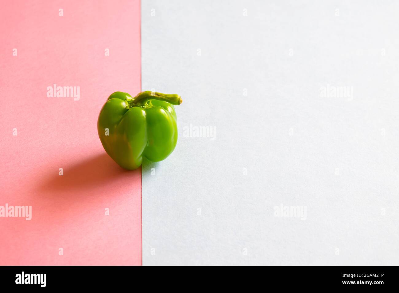 Un peperone verde sullo sfondo dei due fogli di carta colorati con messa a fuoco selettiva e spazio per la copia. Foto Stock