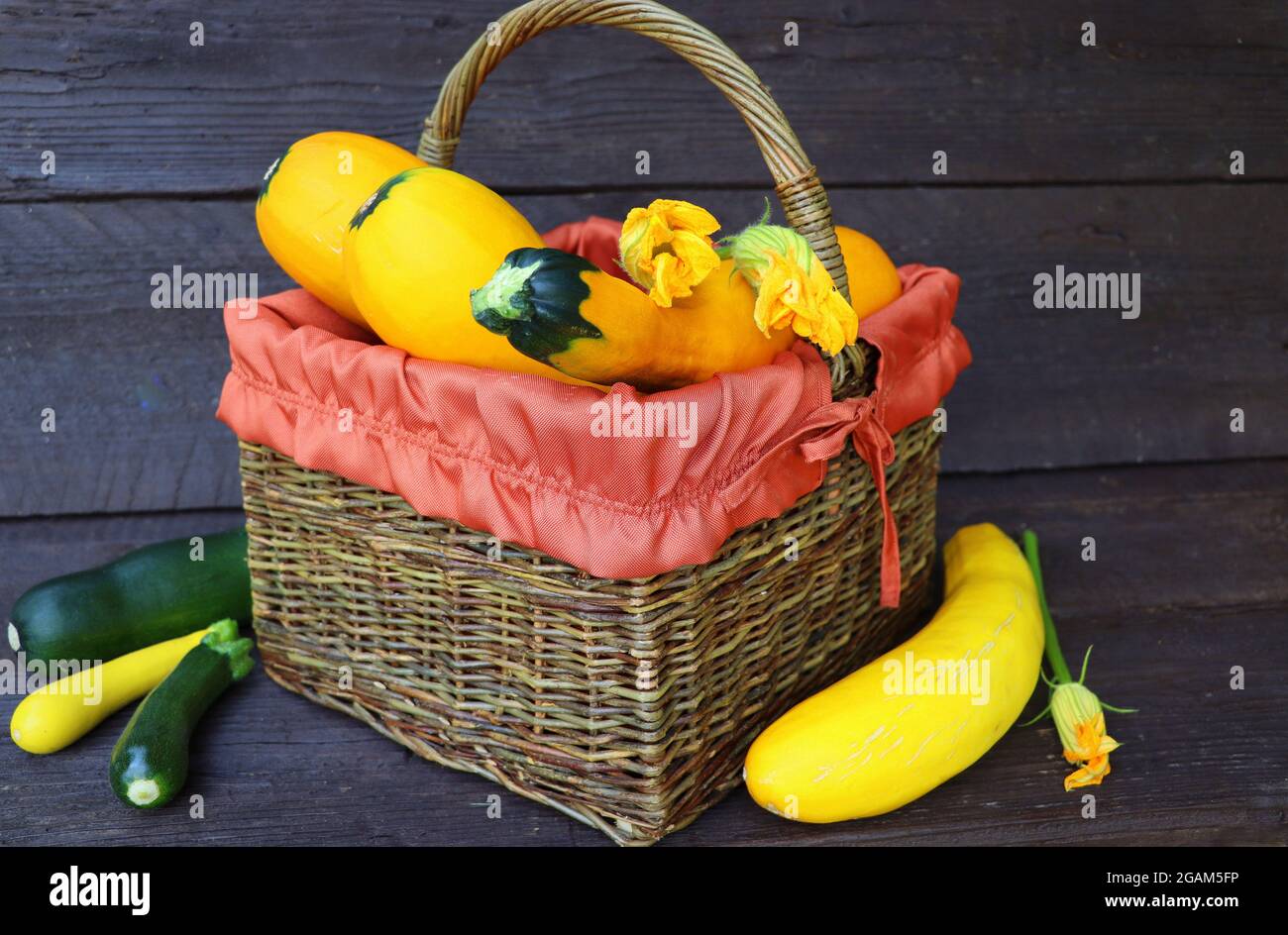zucchine fresche in un cestino. Zucchine con fiori sul vecchio tavolo di legno Foto Stock