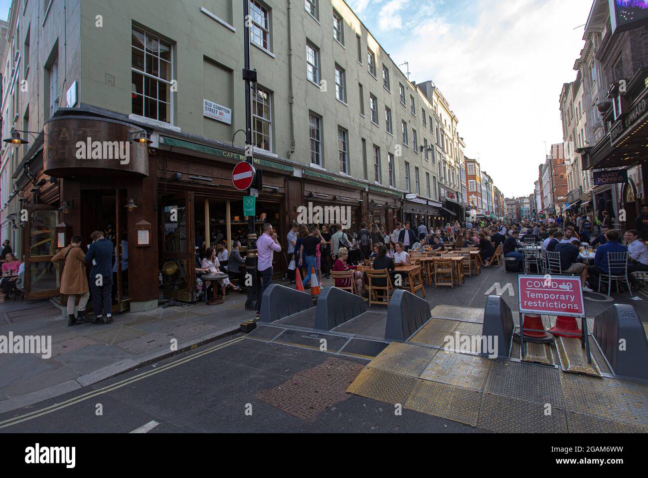 La gente in un ristorante è vista dietro un segno 'di restrizioni temporanee del covid' nel Soho di Londra che solleva tutte le restrizioni sulla vita quotidiana in Inghilterra. Foto Stock