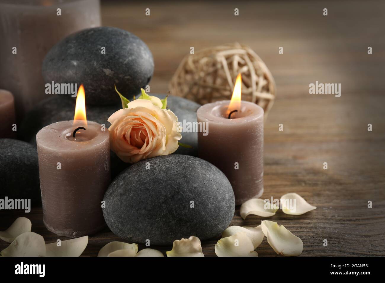 Bella composizione relax di candele, ciottoli e fiori a lume di candela su  sfondo di legno Foto stock - Alamy