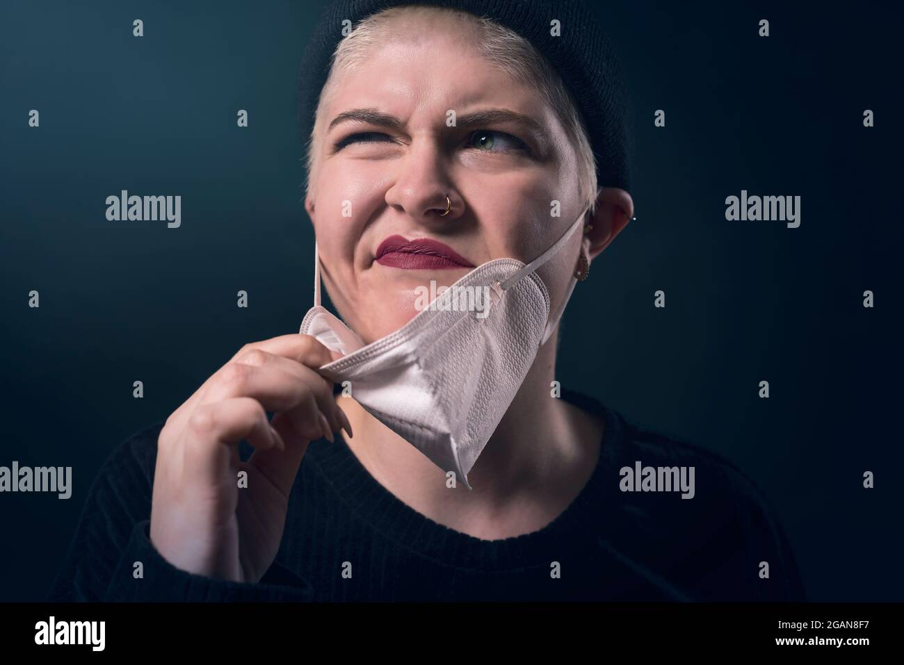 ritratto di una giovane donna infastidita dalla sua maschera protettiva corona Foto Stock