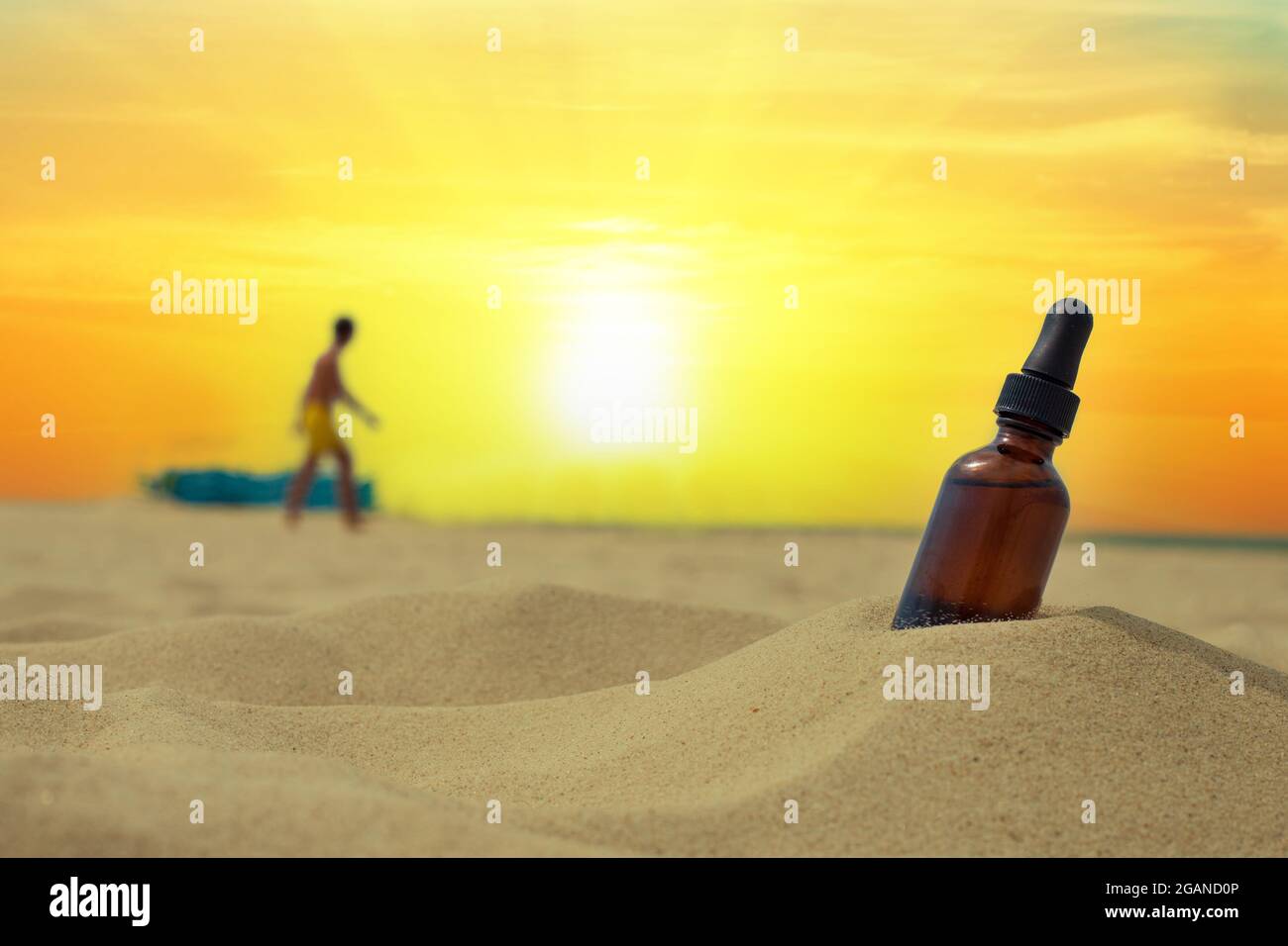 Una bottiglia di olio essenziale su una spiaggia di sabbia. Bottiglia d'olio aromatizzato sulla spiaggia estiva. Olio essenziale per le vacanze estive. Foto Stock