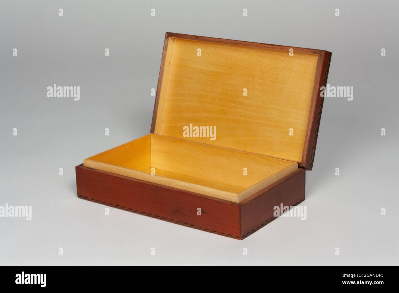 una scatola decorativa in legno con il coperchio aperto su uno sfondo grigio chiaro con spazio per la copia Foto Stock