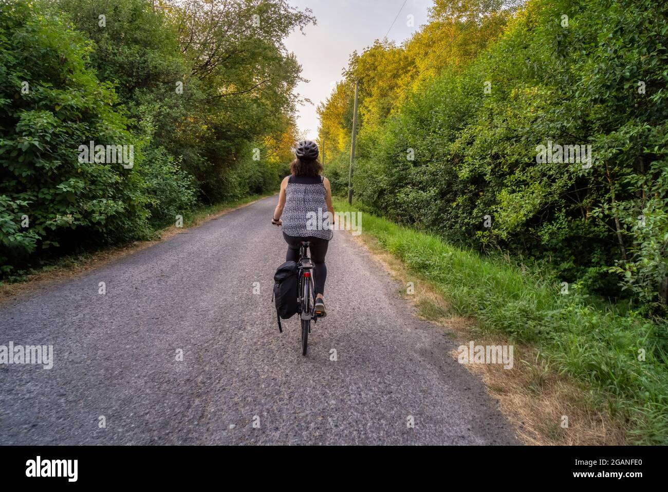 Donna Cacasusiana bianca avventurosa in bicicletta su una strada. Foto Stock