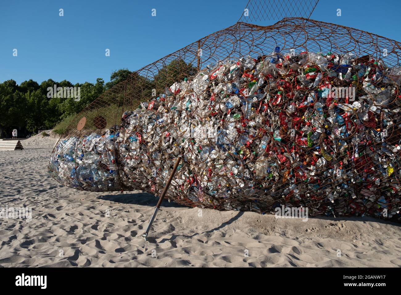 Pärnu, Estonia - 11 luglio 2021: Contenitore gigante di rifiuti a forma di pesce per la raccolta di rifiuti di plastica su una spiaggia pulita. Foto Stock